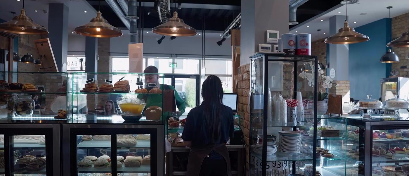 The Le Délice counter: display cabinets of pastries and sandwiches, copper pendant lights and staff serving