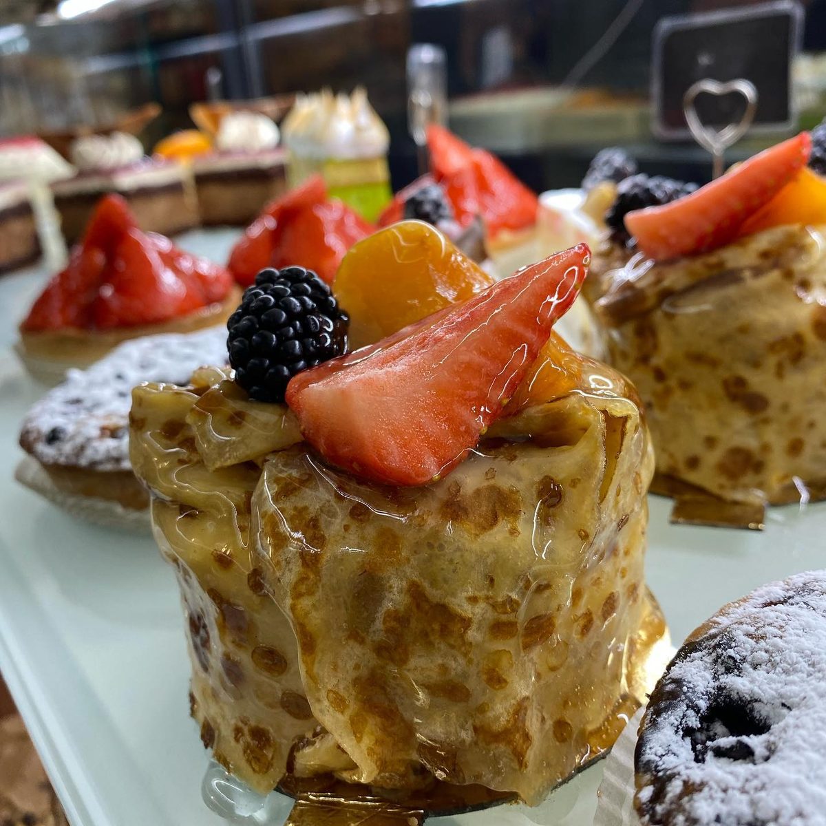 A crêpe cake wrapped in pancakes and topped with fresh fruit
