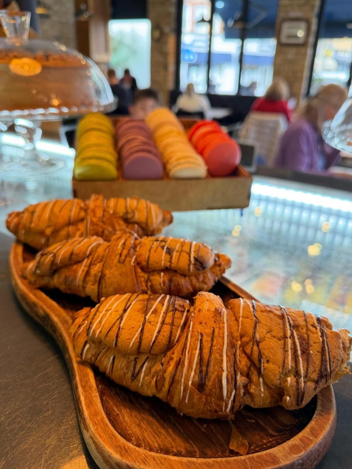 Chocolate-drizzled croissants beside a box of macarons