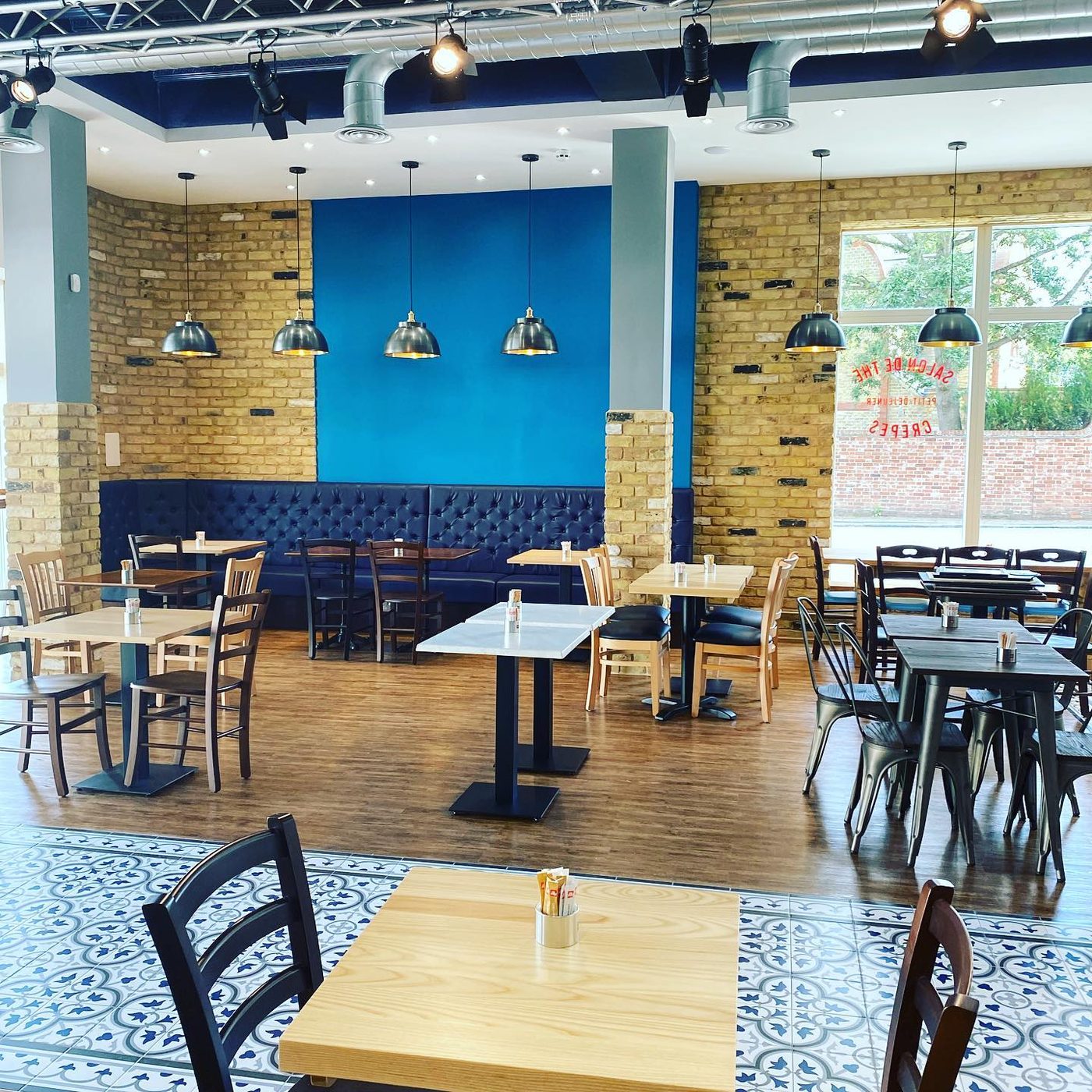 Inside the Hither Green café: exposed brick, a deep blue banquette and patterned floor tiles